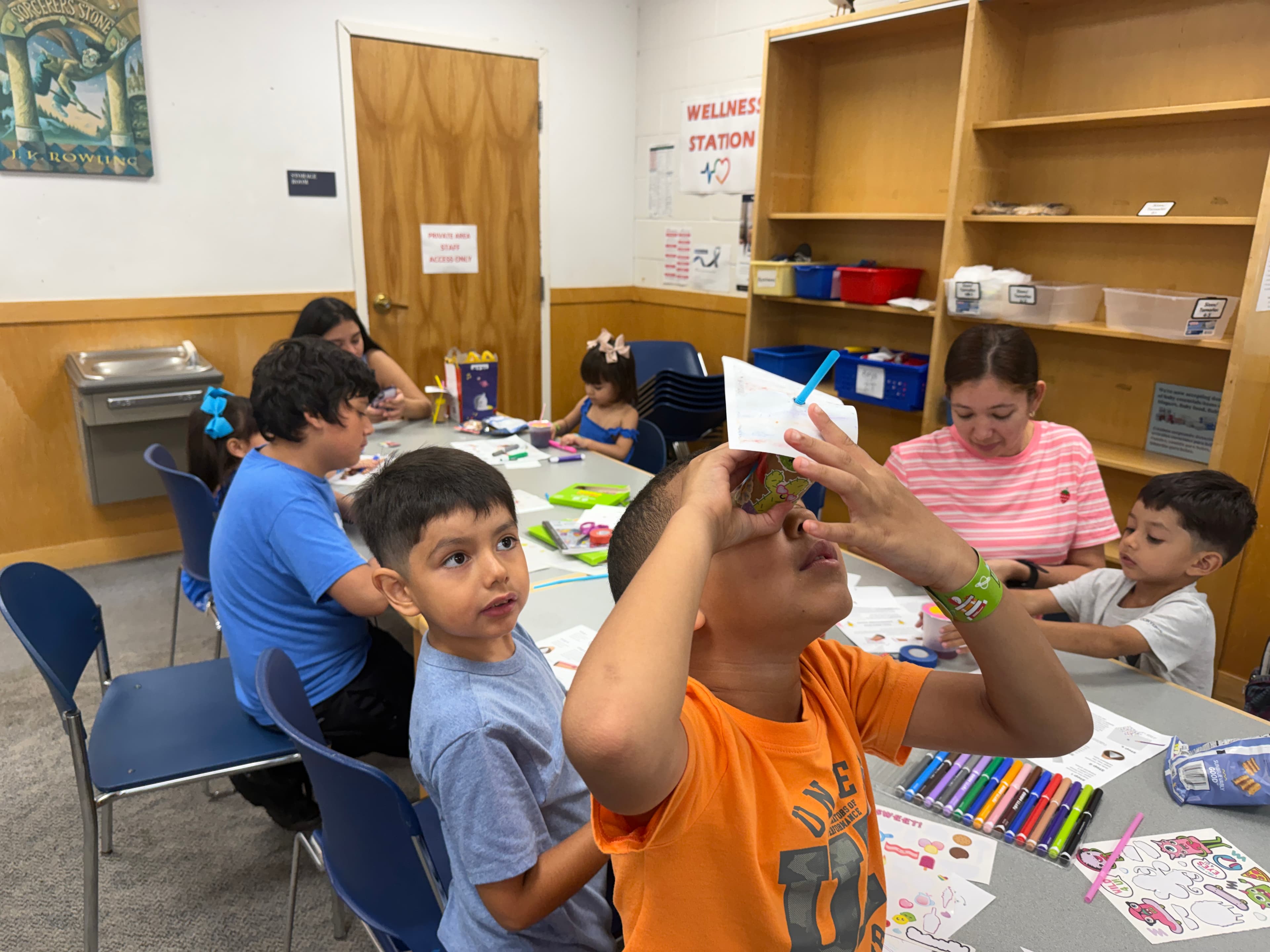 A boy holding his finished kaleidoscope up to the light and looking through it