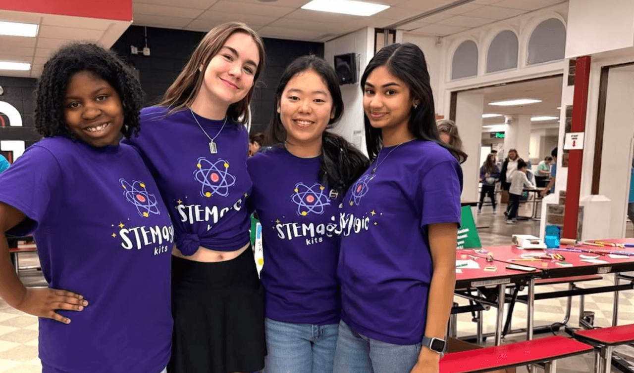 Four STEMagic Kits volunteers in team shirts at the Maker Fair