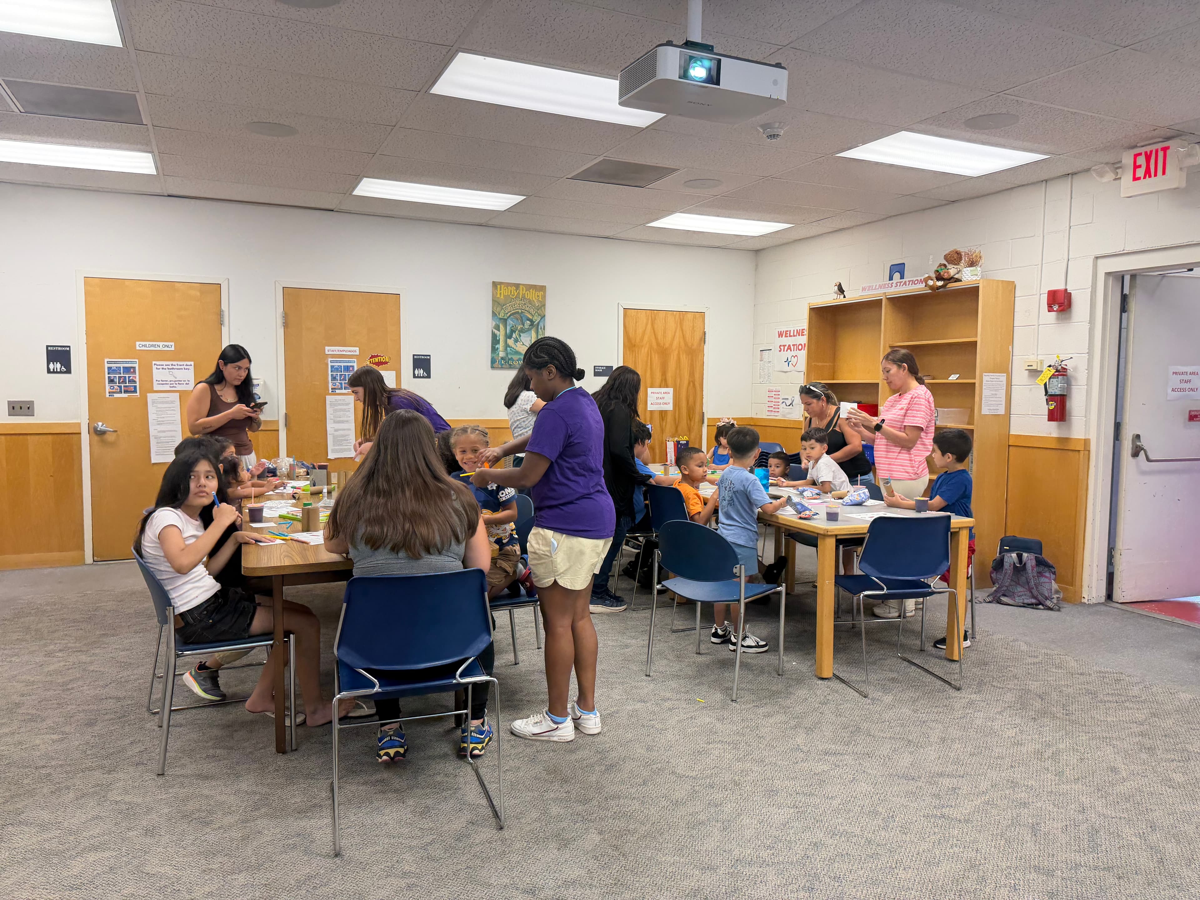 The library’s community room during the workshop, with families spread across two tables of kits